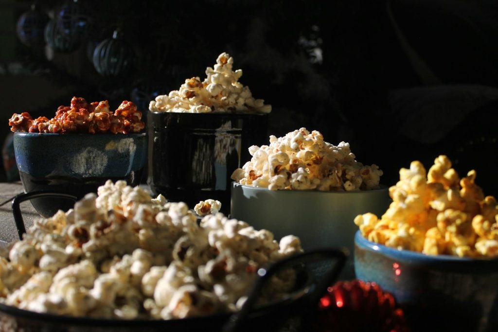 Close-up of assorted gourmet popcorn flavors in bowls, showcasing rich textures and colors.