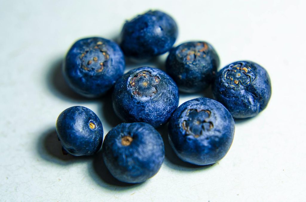 A vibrant close-up of fresh ripe blueberries on a white surface, showcasing their rich texture and color.