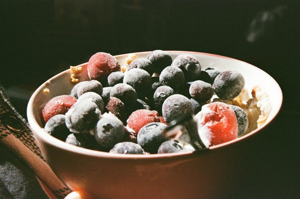 A bowl of frozen blueberries and strawberries capturing morning light.