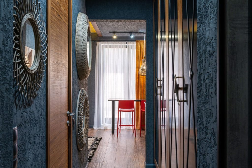 Room with table and chair against corridor with assorted decorative panels on wall in daylight at home