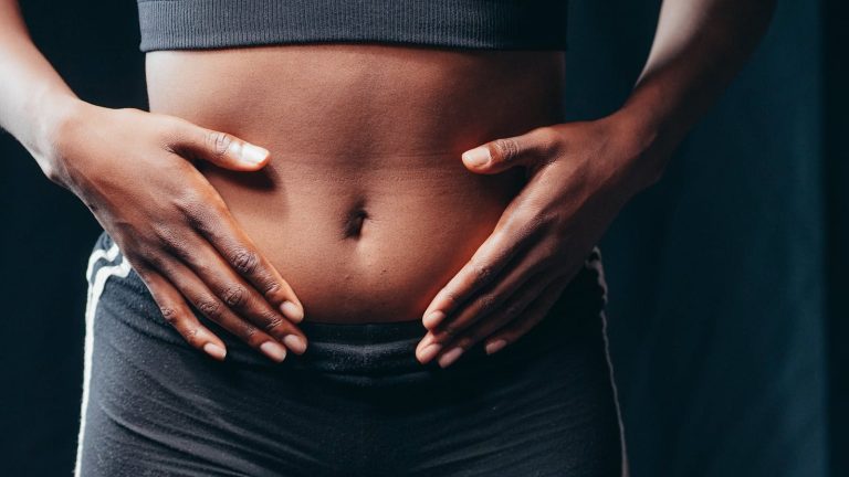Close-up image of hands on abdomen signifying wellness, body awareness, or health check.