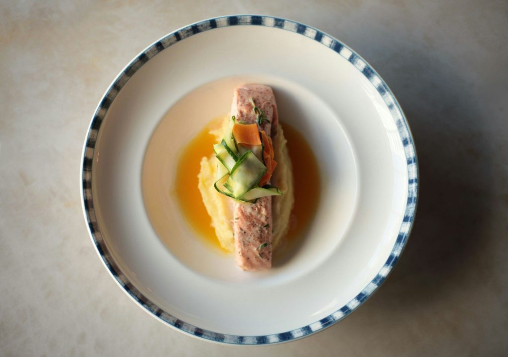 Gourmet dish with salmon and sauce in a bowl.