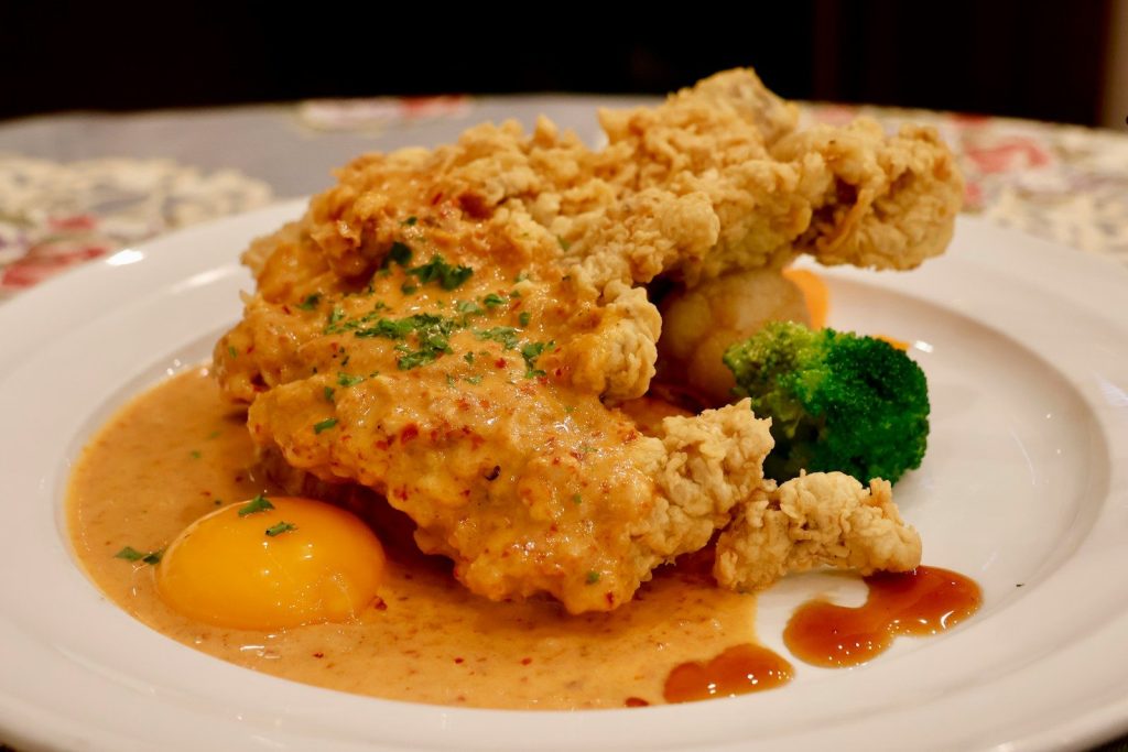 a white plate topped with chicken and broccoli covered in gravy