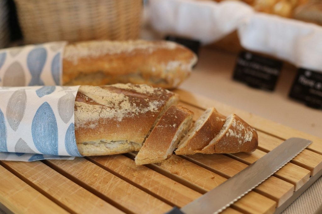Sliced baguette on a wooden board with a bread knife.