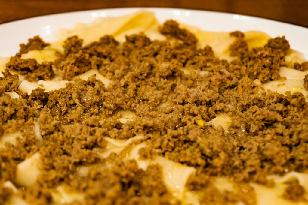 Noodles topped with ground meat on a white plate.