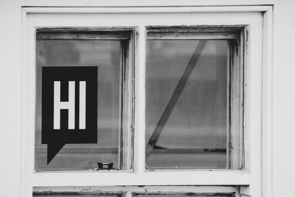 Close-up of a vintage window with a bold HI message in black and white.