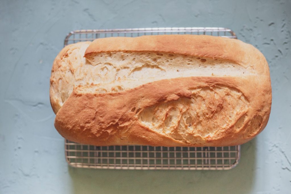 Golden brown homemade bread loaf cooling on a wire rack, ready to serve and enjoy.