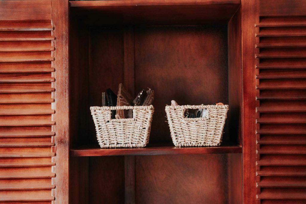 Two woven baskets on a wooden shelf within a cabinet, providing storage decor.