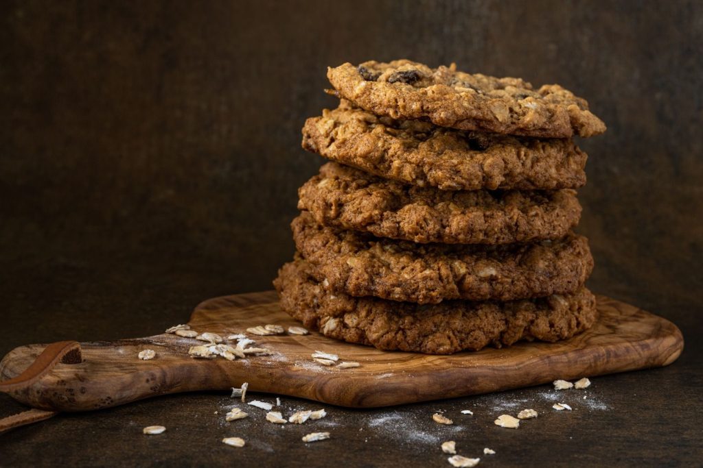 Delicious oatmeal raisin cookies stacked on a wooden board, perfect for dessert lovers.