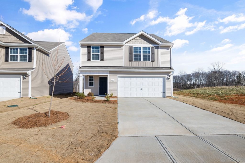 Contemporary two-story home with a large driveway in a suburban setting.