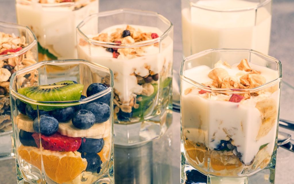 Delicious fruit and yogurt parfait with granola in clear glass jars.