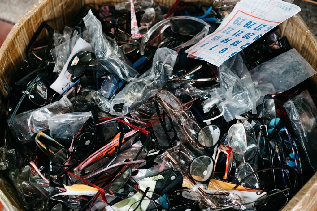 A diverse collection of eyeglasses and sunglasses in a cardboard box, showcasing various styles.