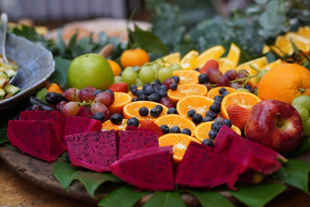 A colorful array of fresh fruits including dragon fruit, oranges, grapes, and berries displayed beautifully on a platter.
