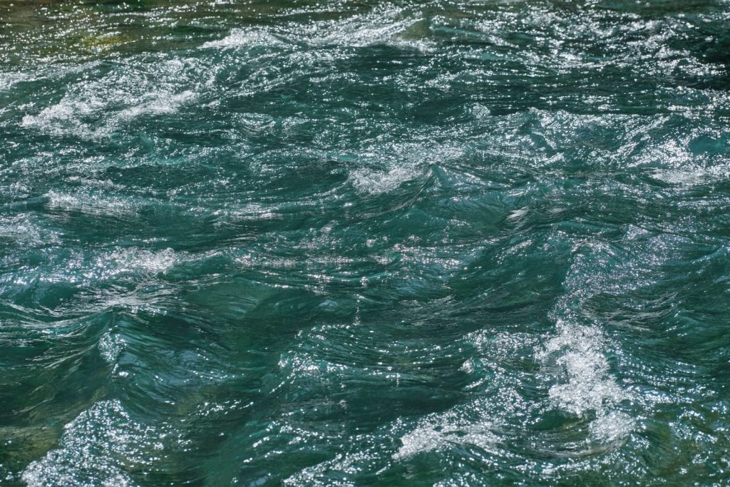 Vibrant close-up of a river with shimmering waves reflecting sunlight.