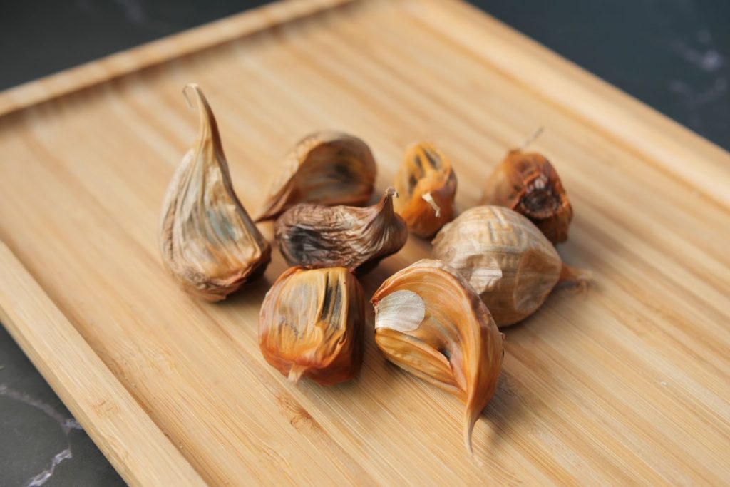 A detailed close-up of black garlic cloves on a wooden cutting board. Perfect for culinary presentations.
