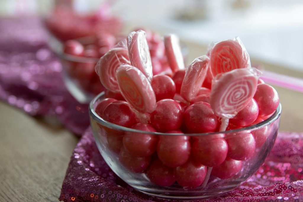 Close-up of pink lollipops and candies in a glass bowl. Perfect for a sweet-themed party setting.