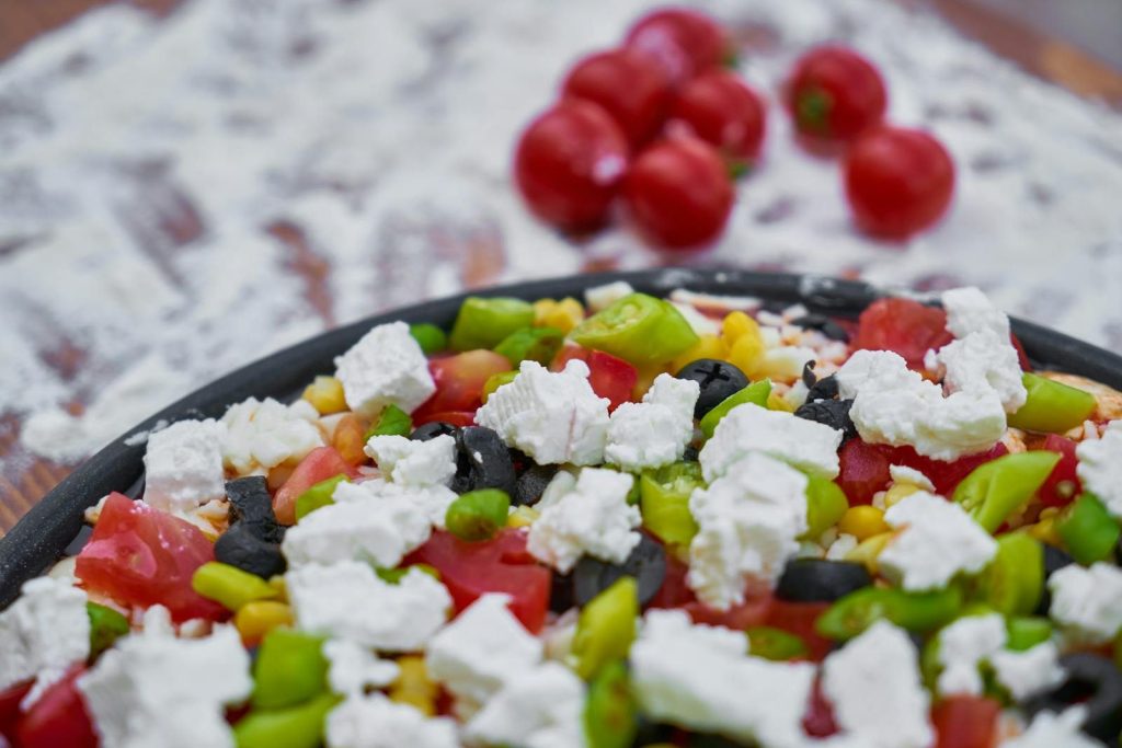 Close-up of a fresh vegetarian pizza topped with feta cheese, olives, and vegetables.