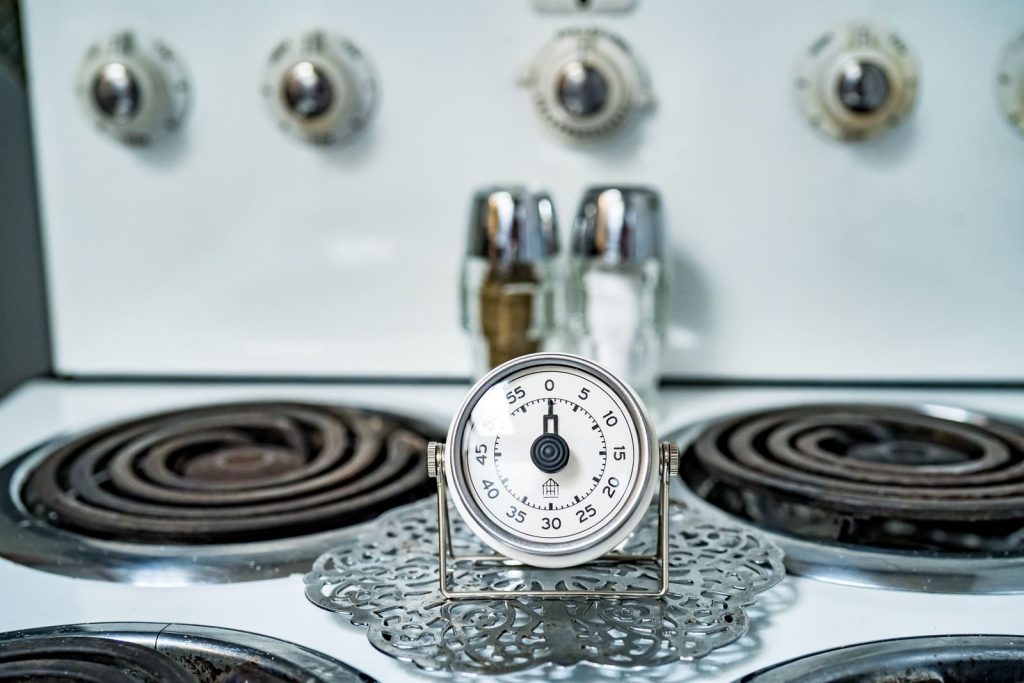 Close-up of a classic analog kitchen timer on a vintage gas stove, perfect for cooking themes.