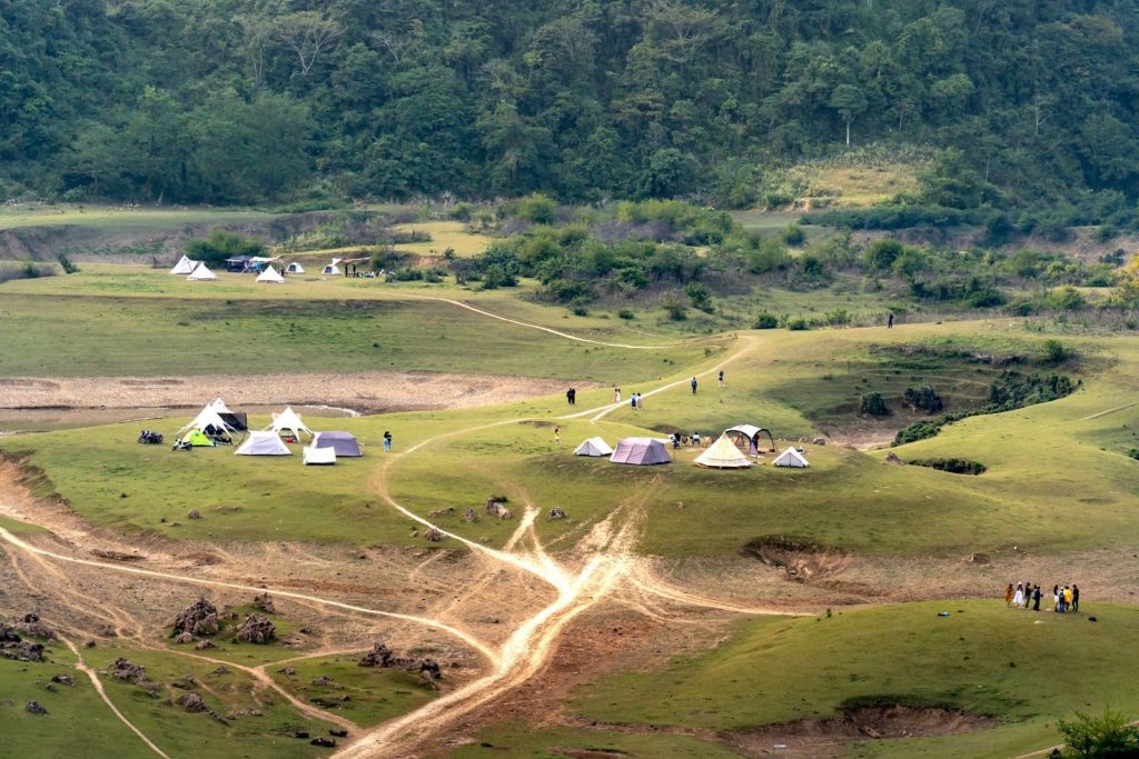 Aerial view of a scenic campsite in the countryside featuring multiple tents and lush greenery.