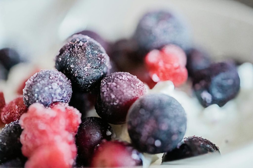 Close-up of frosted berries on a creamy dessert, highlighting vibrant colors and textures.