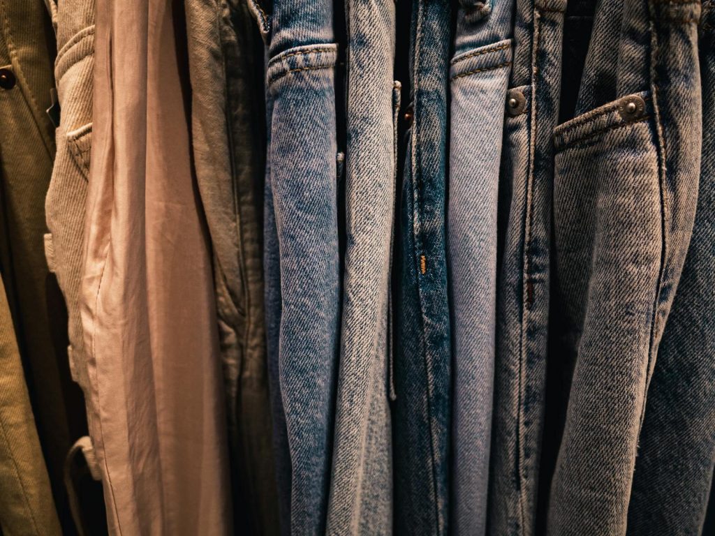 Close-up of various denim jeans hanging on a rack, showcasing different shades and styles.