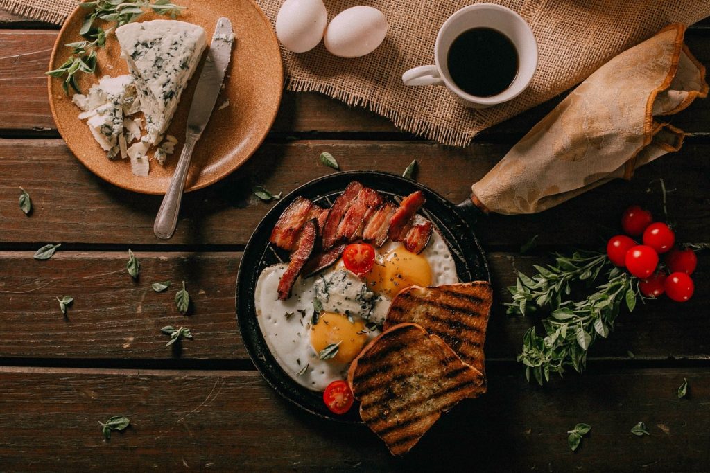 Delicious rustic breakfast spread with eggs, bacon, cheese, and toast on a wooden table.