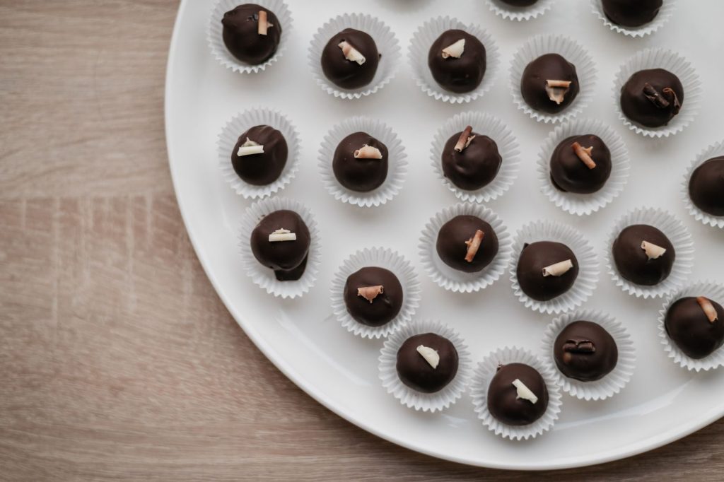Top-down view of assorted chocolate pralines elegantly arranged on a white plate.
