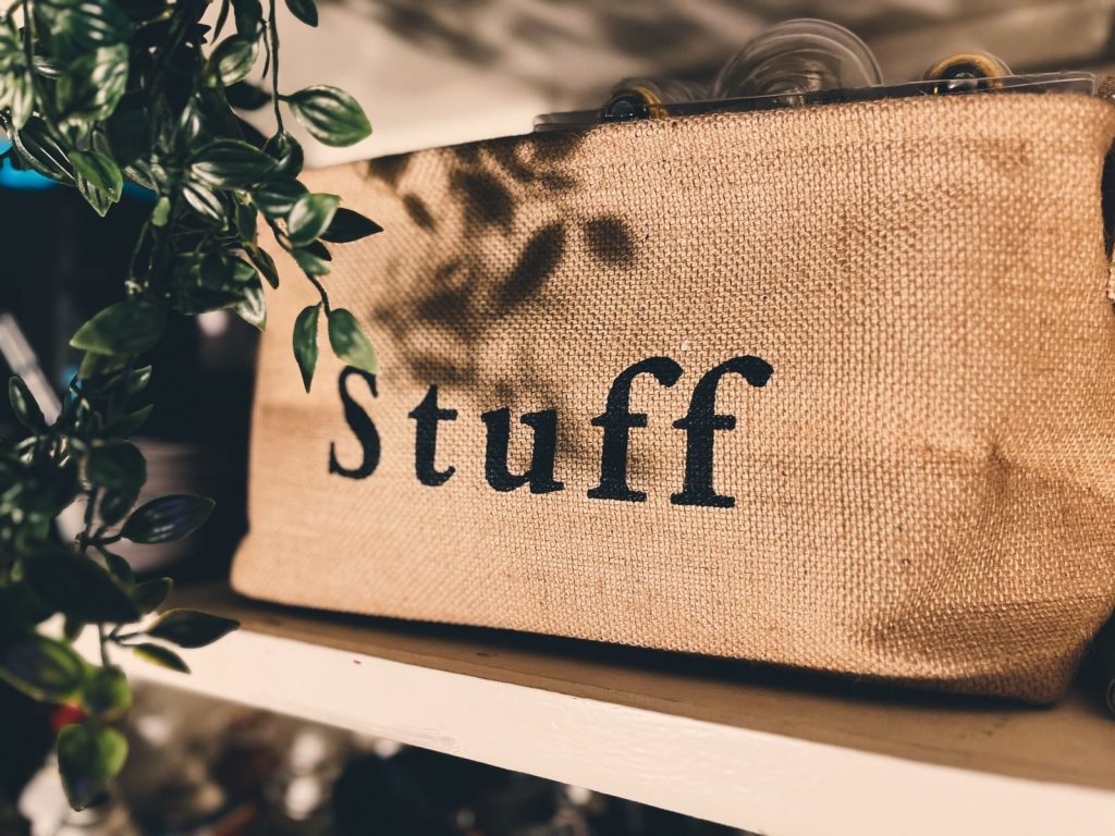 Close-up of a burlap bag labeled 'Stuff' on a wooden shelf with plants.