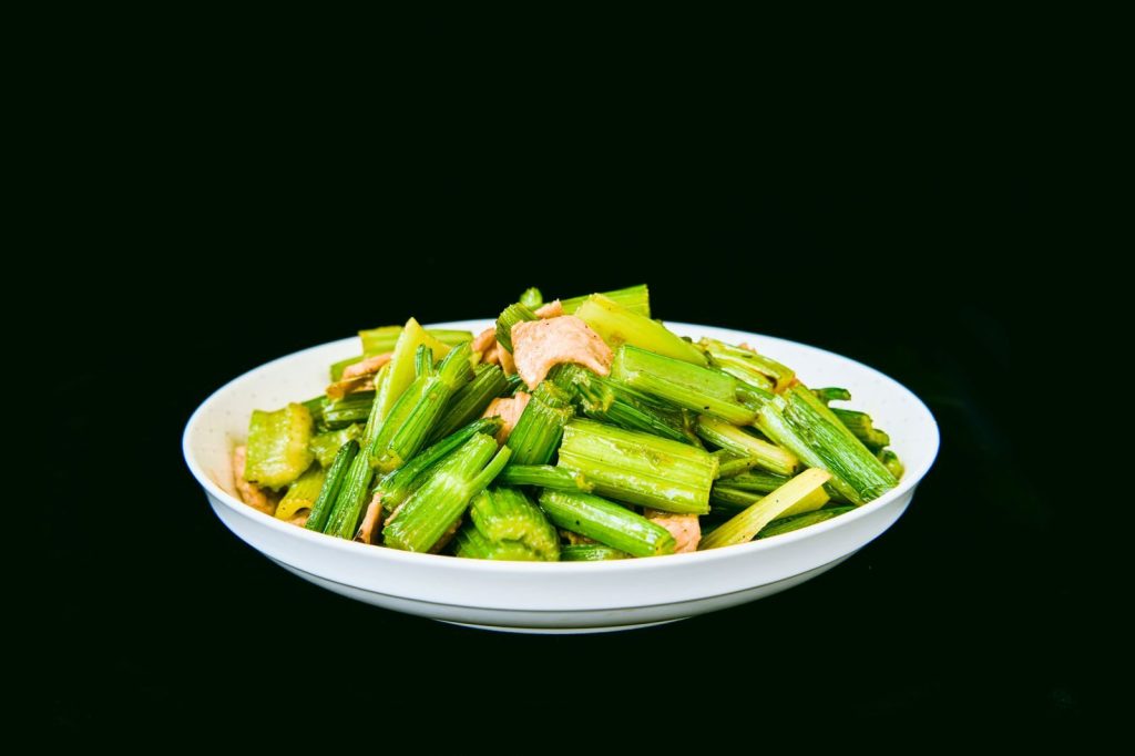 Appetizing plate of celery and salmon salad against black background, perfect for healthy lunch ideas.