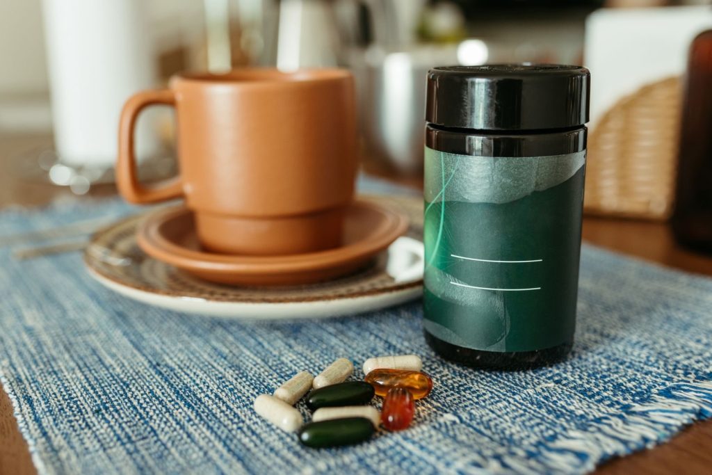 A variety of capsules near a ceramic mug and container on a table.