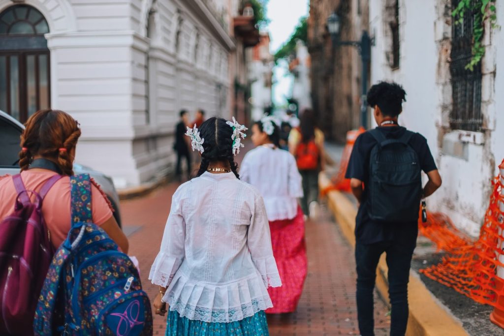 People in traditional attire walking through a vibrant city street, showcasing cultural diversity.