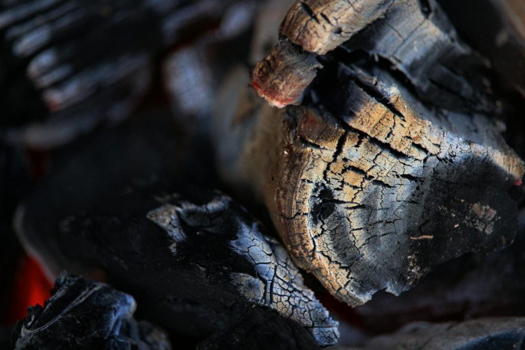 Detailed closeup of burning charcoal showing intricate cracks and glowing embers.