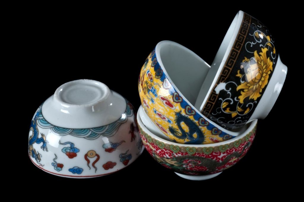 Close-up of artistic ceramic bowls with intricate patterns against a black backdrop.