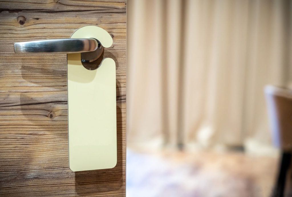 A close-up of a wooden door with a metallic handle and blank hanger in a cozy interior setting.