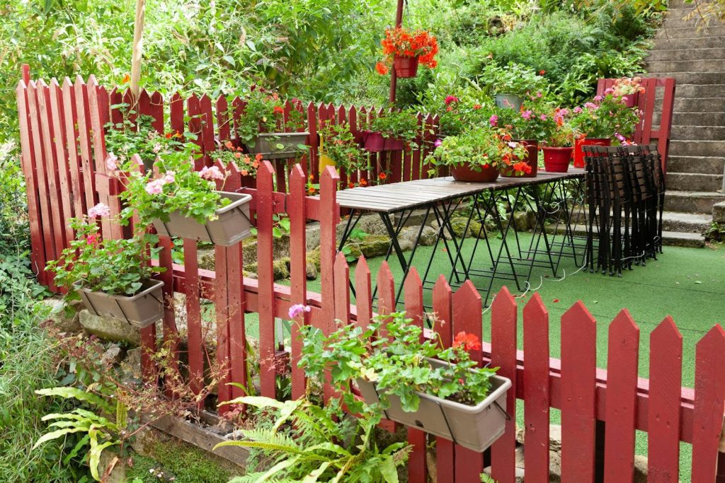 A vibrant garden terrace with red fence and flowers in Dinan, Brittany, France.