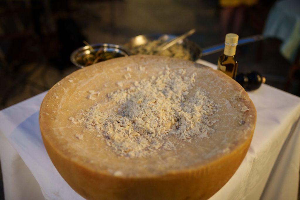 Close-up of a Parmesan wheel with freshly grated cheese on a table ready for a gourmet dish.