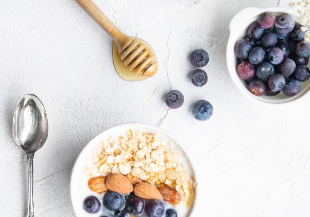 Top view of a nutritious breakfast with blueberries, nuts, and honey on a white background.