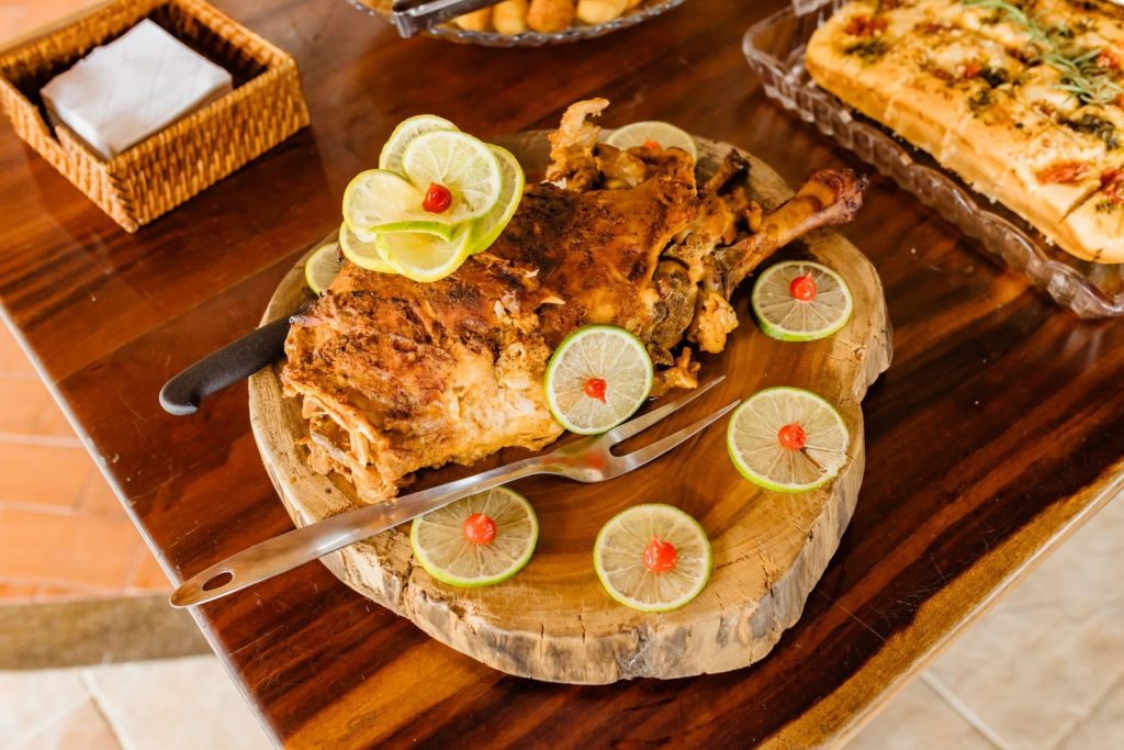 Delicious roasted lamb served with lime slices and garnishes on a wooden platter.