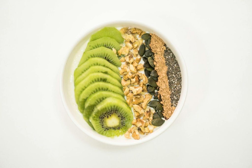 A vibrant smoothie bowl with kiwi, nuts, seeds, and yogurt, ideal for a nutritious breakfast.