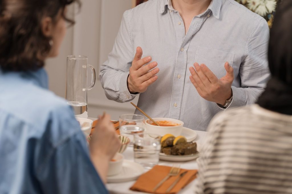 Group of adults sitting around a table, engaging in conversation over a meal.