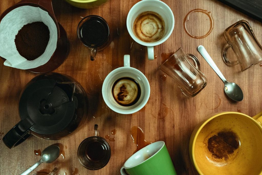 Artistic top view of empty coffee cups with spilled stains on a wooden table.