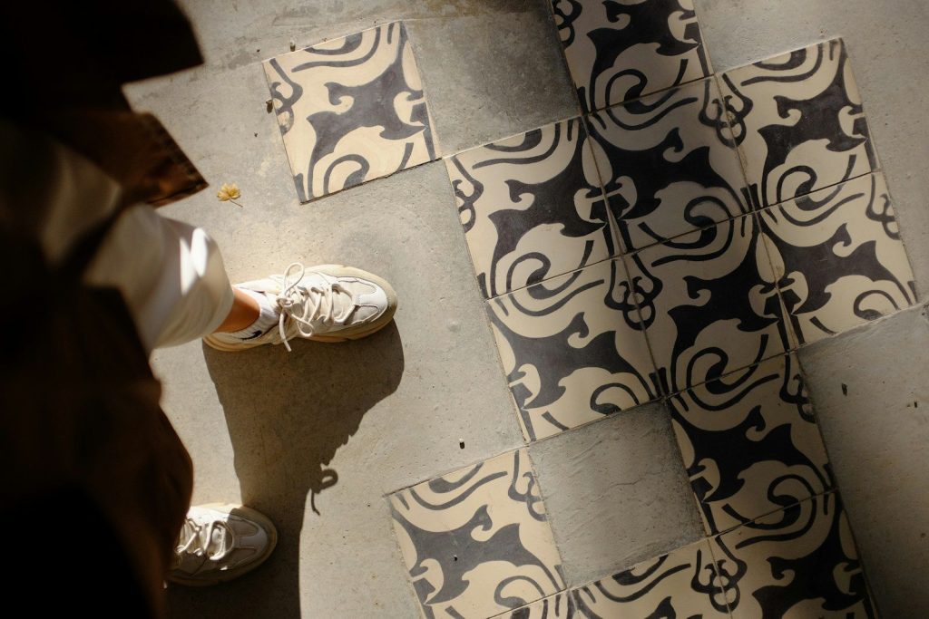 person in white sneakers standing on black and white floor tiles