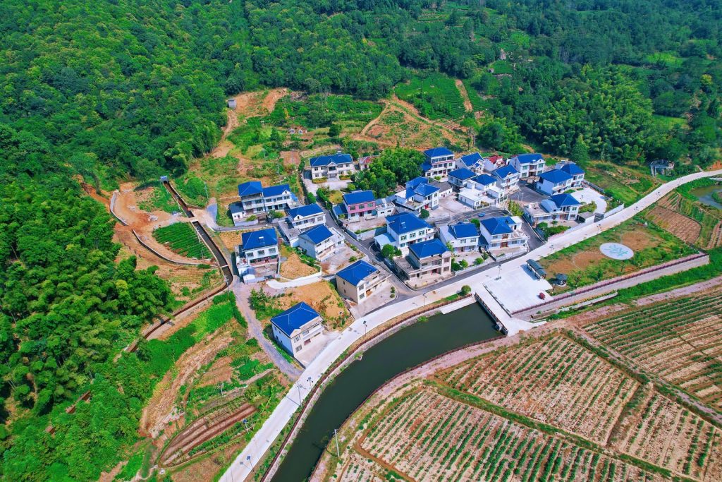 Aerial view of a vibrant village surrounded by lush forests in Ji'an, Jiangxi, China.