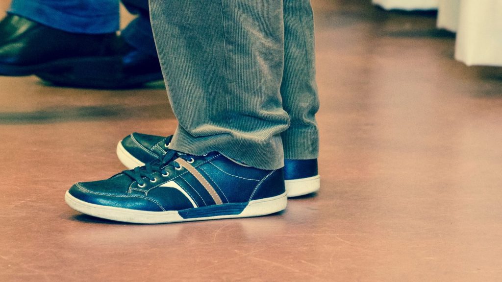 Close-up of a person wearing casual sneakers with denim pants indoors.