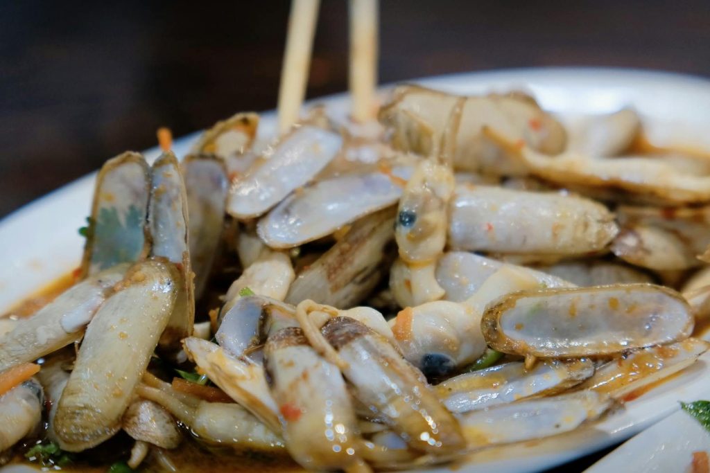 A plate of freshly prepared razor clams served in a savory sauce, ideal for seafood lovers.