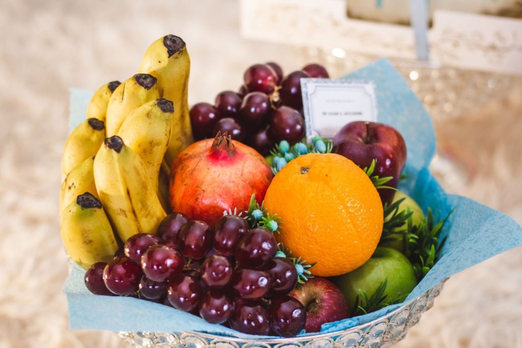 Vibrant arrangement of mixed fruits including bananas, grapes, and oranges in a decorative setting.
