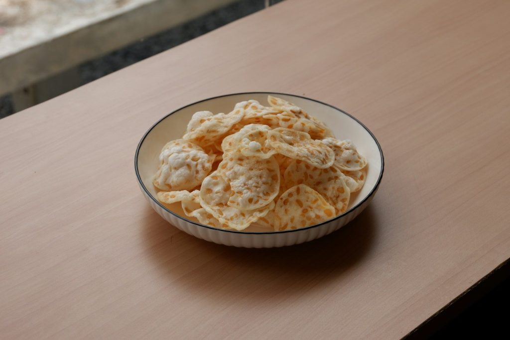 a bowl filled with cheetos sitting on top of a wooden table