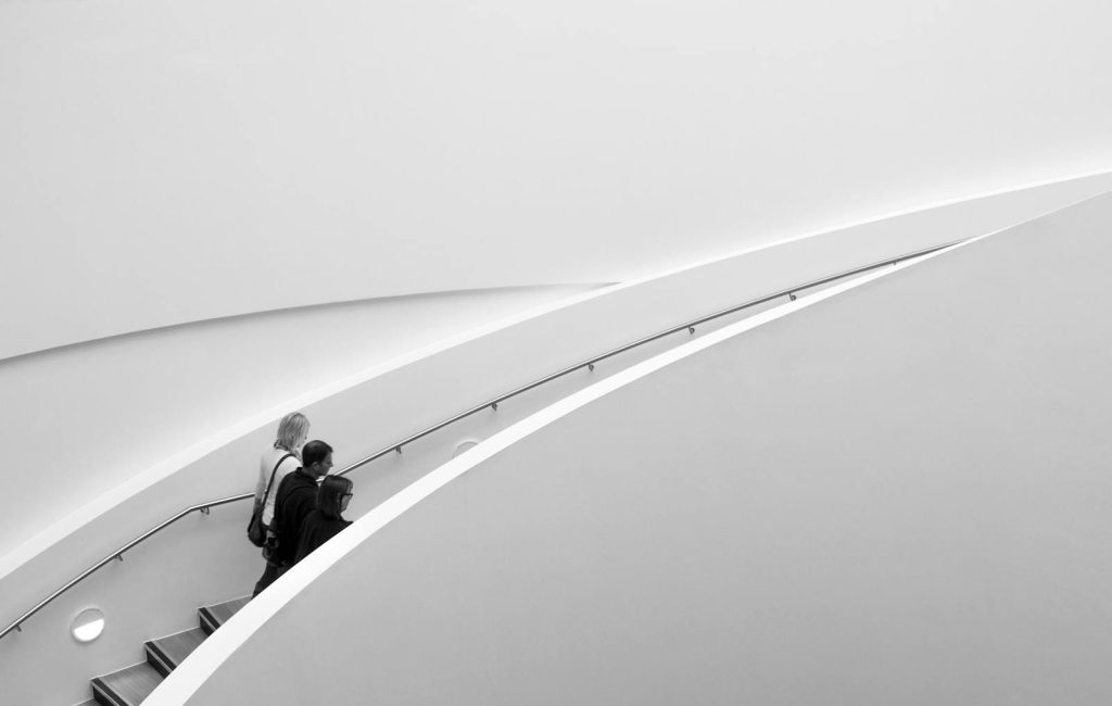 Two people on a sleek staircase, minimalistic architecture in black and white.