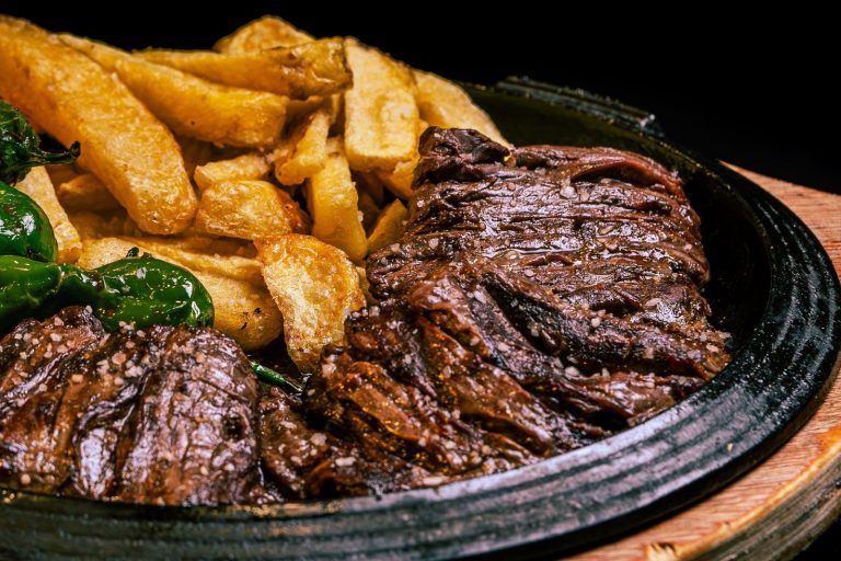 Juicy grilled steak paired with crispy fries and green peppers on a rustic plate.