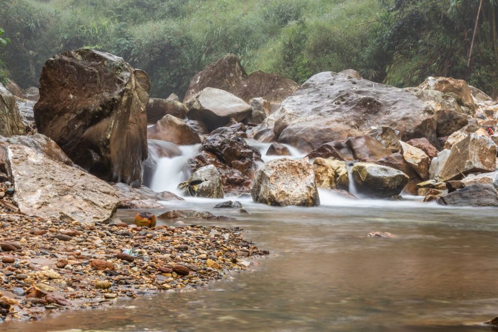 Flowing stream with large boulders in a tranquil mountain setting captured in fall.